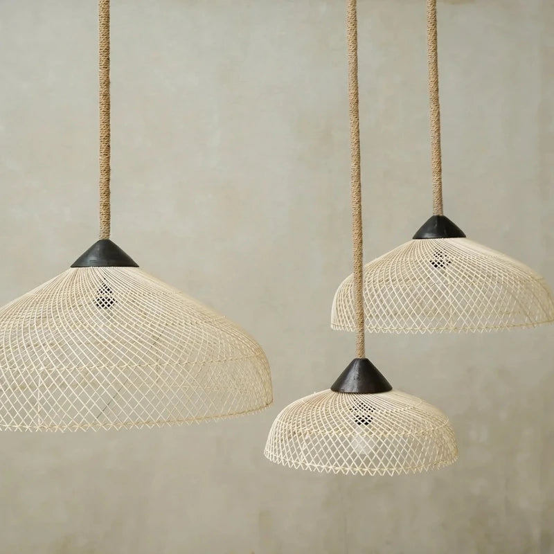Détail de trois abat-jours en rotin de tailles variées suspendus avec des câbles en corde.