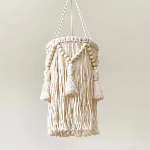  abat-jour nordique en macramé avec des perles et des franges décoratives suspendu au plafond, éclairé.