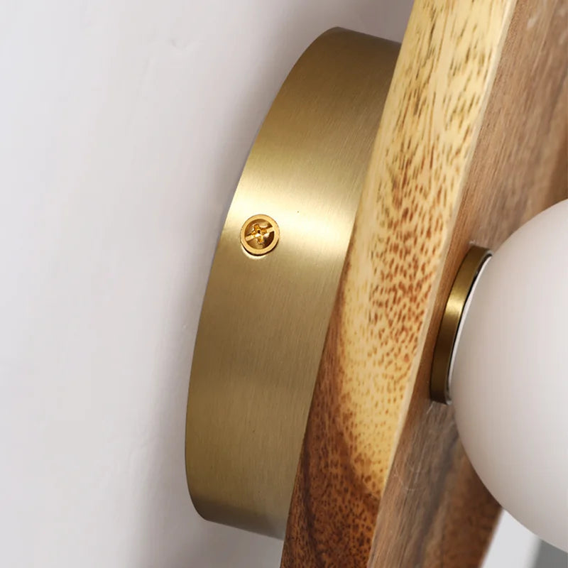 Gros plan sur l’applique murale en bois naturel montrant les détails du design avec l'abat-jour en verre et le bois poli.
