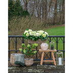 Panier en rotin naturel rond rempli d’hortensias blancs et feuilles vertes