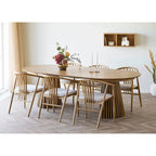 Table ovale en bois clair avec base cannelée et chaises rembourrées blanches