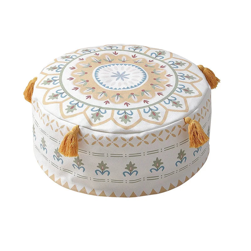Housse de pouf rond avec un motif jaune et blanc, ornée de pompons, pour une décoration bohème et lumineuse.