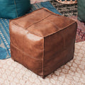 Housse de pouf marocain marron posée sur un tapis oriental, parfaite pour un intérieur authentique.