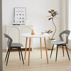 Chaises contemporaines grises autour d’une table blanche avec pieds en bois, ambiance minimaliste et moderne.
