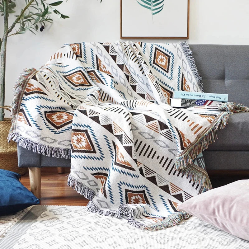 Plaid aztèque à franges posé sur un canapé avec des motifs ethniques colorés