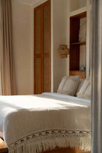 Lit avec duvet blanc, plaid beige en coton à franges et coussins texturés