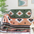  Plaid ethnique vert et terracotta avec motifs géométriques, posé sur un canapé