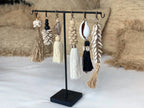 Boucles bohèmes à glands, coquillages et matériaux naturels sur support noir