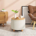 Pouf de rangement rond utilisé comme table d’appoint, décoré avec une tasse et une assiette.