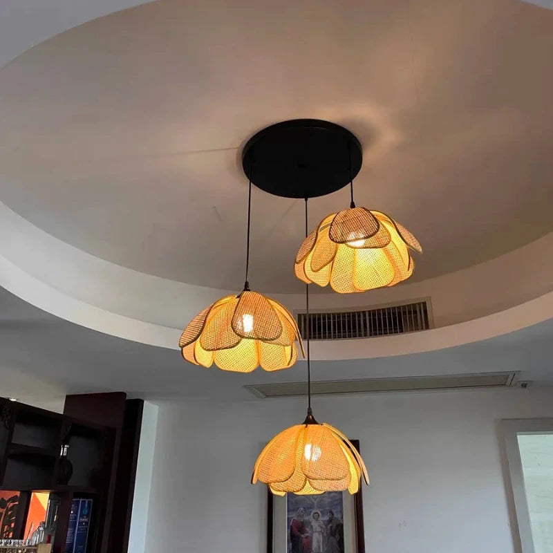Lustre en rotin à 3 lampes allumé, créant un jeu de lumière tamisée dans la pièce.