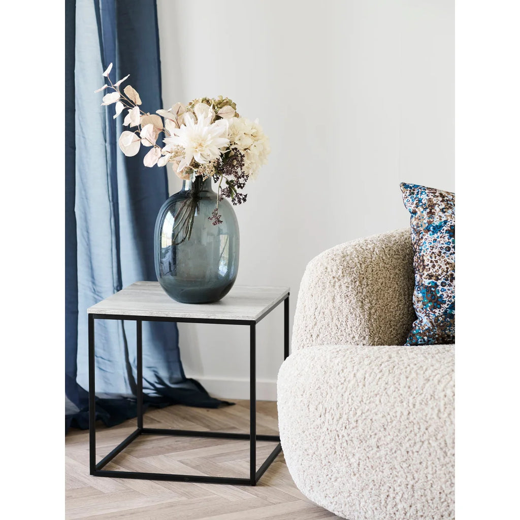 Vase gris foncé élégant avec fleurs blanches sur table d’appoint effet travertin