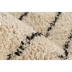 Tapis tufté écru avec motifs noirs en coton et franges, vue en gros plan